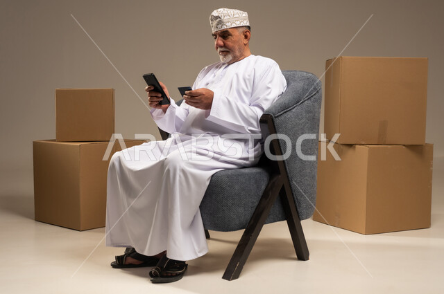 رجل عماني مسن يستخدم الهاتف للتسوق الإلكتروني