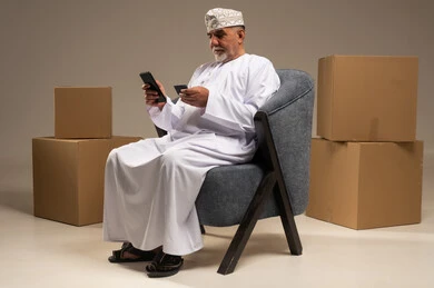 رجل عماني مسن يستخدم الهاتف للتسوق الإلكتروني