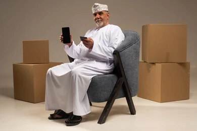 رجل عُماني مسن يستخدم الهاتف للتسوق الإلكتروني
