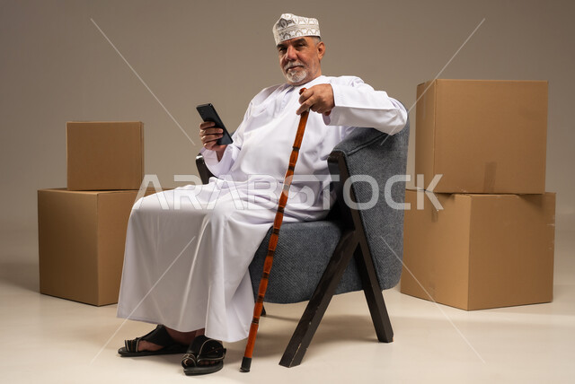Elderly Omani Man in Traditional Dress with Smartphone