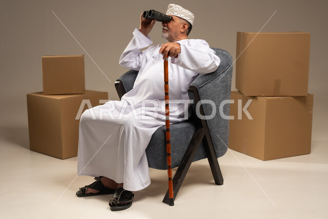 رجل عماني يستخدم المنظار مع صناديق شحن
