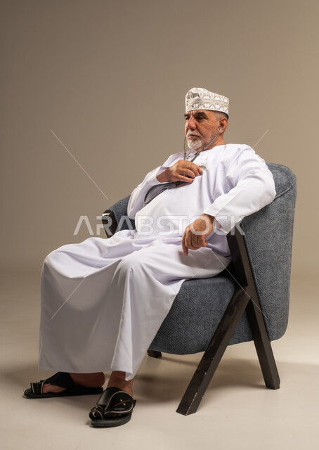 رجل عماني مسن يستخدم سماعة طبية في الاستوديو