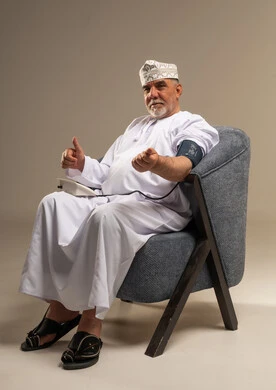 رجل عماني مسن يستخدم جهاز قياس ضغط الدم
