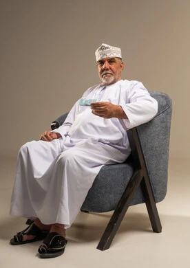 Elderly Omani Man in Traditional Dress Holding Card