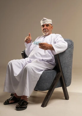 رجل عماني مسن يحمل بطاقة بنكية وإيماءة نجاح