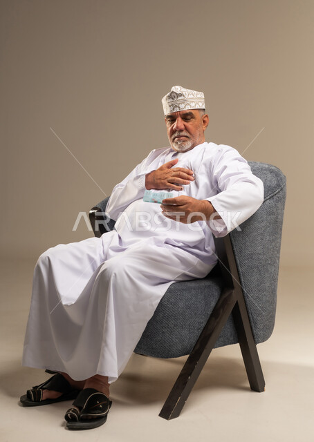 رجل عُماني مسن يمسك بالدواء في الاستوديو