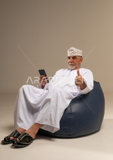رجل عماني مسن يستخدم الهاتف الذكي في الاستوديو