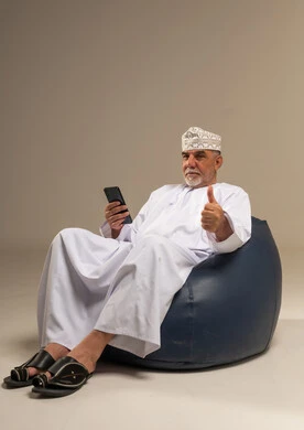 رجل عماني مسن يستخدم الهاتف الذكي في الاستوديو