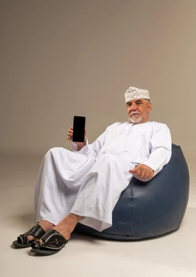 رجل عُماني مسن يحمل هاتفاً ذكياً في الاستوديو