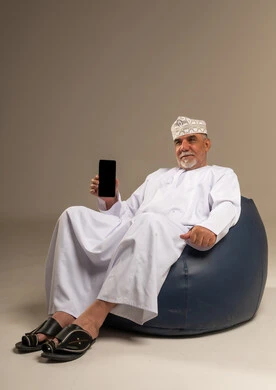 Omani Senior Man Sitting on Beanbag with Smartphone