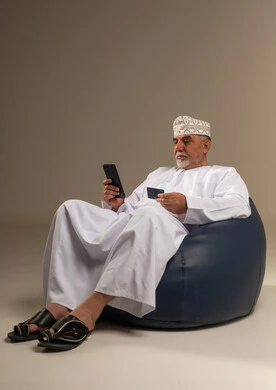 رجل عماني يستخدم الهاتف الذكي والبطاقة الائتمانية