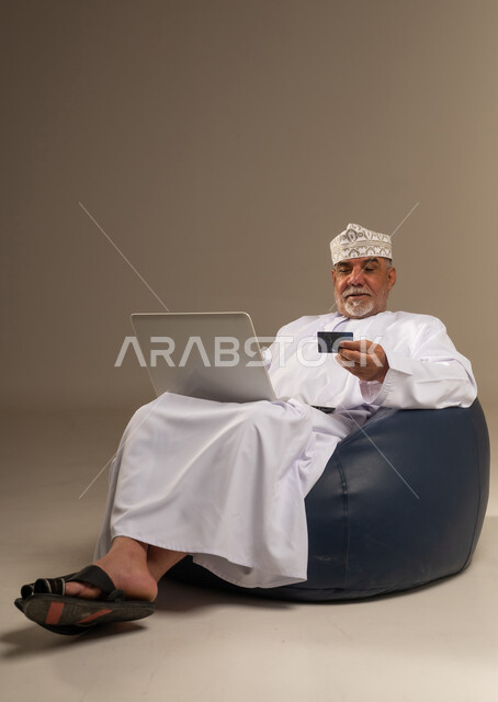 رجل عماني مسن يستخدم المحمول والبطاقة الائتمانية