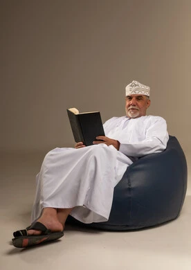 رجل عُماني مسن يقرأ كتاب بالزي التقليدي في الاستوديو