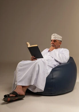 رجل عُماني مسن يقرأ كتاباً في الاستوديو