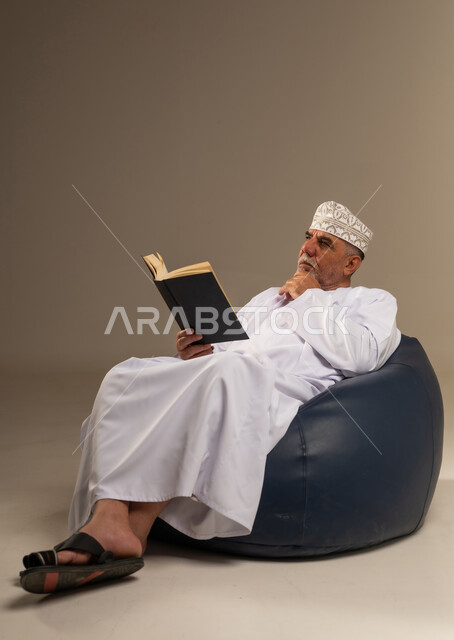 رجل عماني بالزي التقليدي يقرأ في استوديو