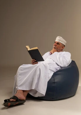 رجل عماني بالزي التقليدي يقرأ في استوديو
