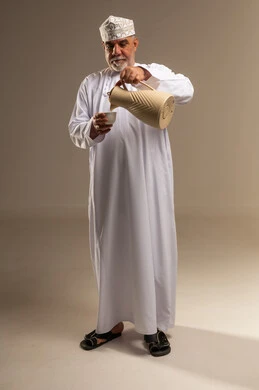 Elderly Omani Man Pouring Coffee in Traditional Attire