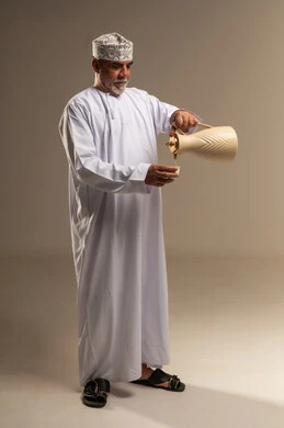 رجل عُماني بالزي التقليدي يسكب القهوة