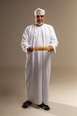Omani Man in Traditional Dress Holding Luqaimat