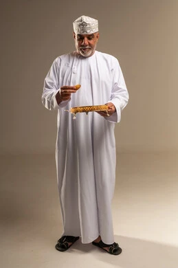 رجل عُماني مسن يتناول التمر بالزي التقليدي