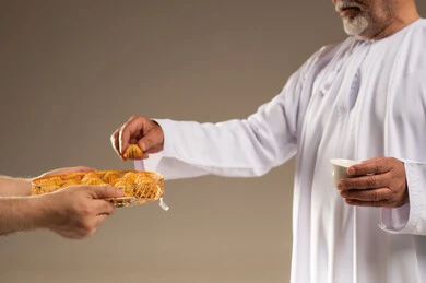 رجل عربي مسن يتناول المعمول والقهوة العربية التقليدية