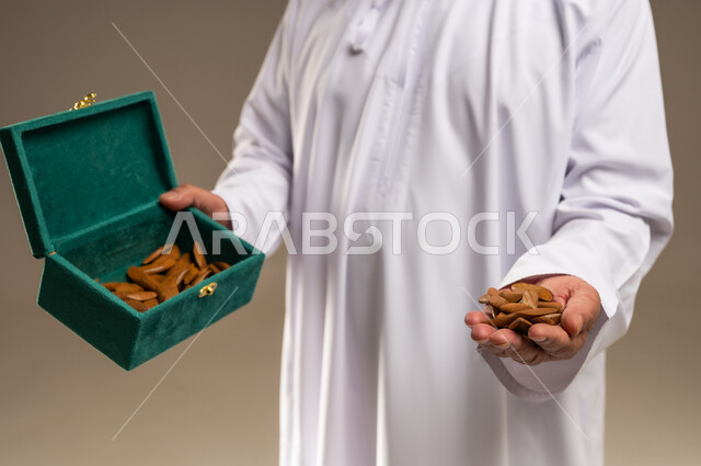 رجل سعودي يمسك بكسر عود البخور في صندوق أخضر