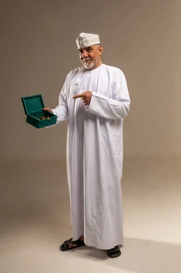 رجل عماني بالزي التقليدي يشير لصندوق مجوهرات