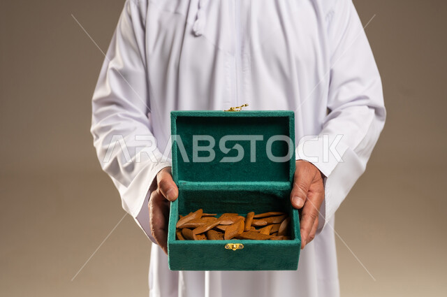 رجل سعودي يحمل صندوق خشب العود الطبيعي