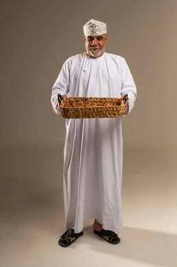 Omani Man in Traditional Dress Holding Dates Tray