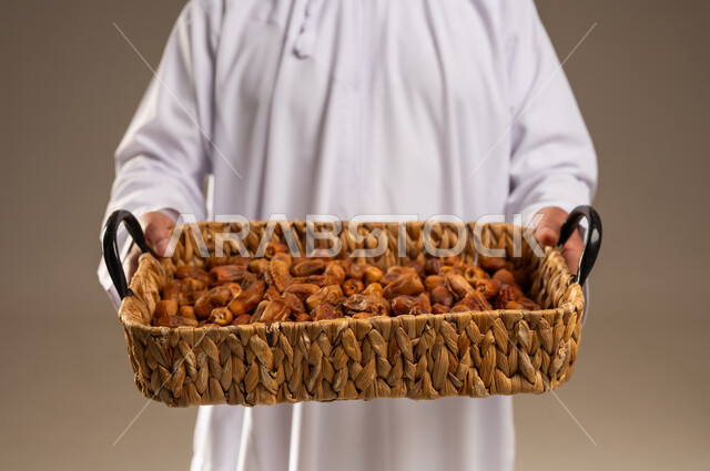 رجل سعودي يحمل سلة خوص مليئة بالتمر