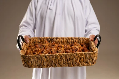 رجل سعودي يحمل سلة خوص مليئة بالتمر