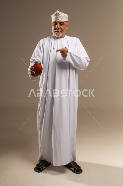رجل عماني يحمل وعاء عسل بالزي التقليدي
