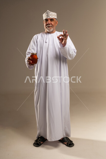 رجل عماني يحمل جرة عسل مع إيماءة الرضا