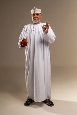 رجل عماني يحمل جرة عسل مع إيماءة الرضا