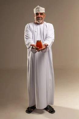 رجل عُماني مسن يحمل جرة عسل في الاستوديو