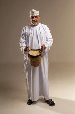 رجل عماني مسن يحمل سلة حبوب بالزي التقليدي