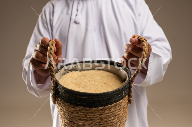 رجل سعودي يحمل سلة أرز تقليدية في الاستوديو