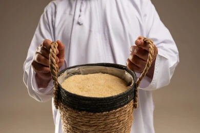 رجل سعودي يحمل سلة أرز تقليدية في الاستوديو