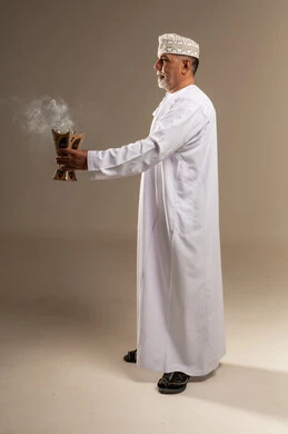 رجل عُماني بالزي التقليدي يمسك بمبخرة في استوديو