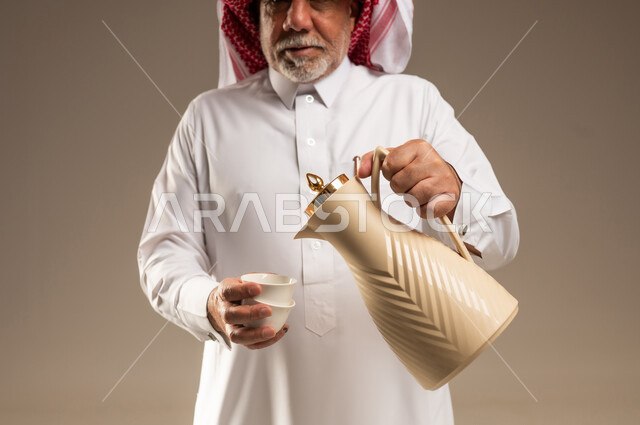 رجل سعودي مسن يسكب القهوة العربية من الدلة