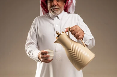 رجل سعودي مسن يسكب القهوة العربية من الدلة