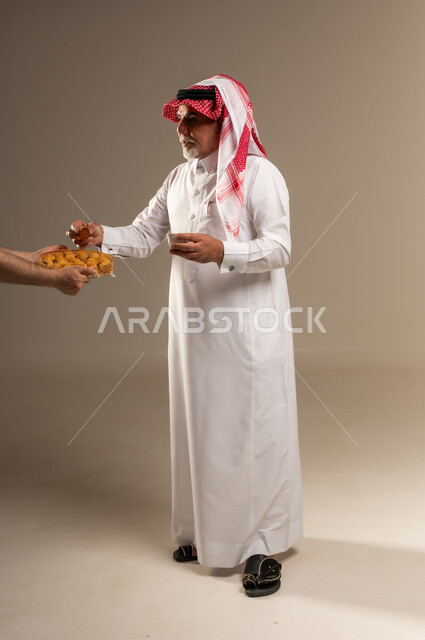 رجل سعودي مسن يتناول حلويات شعبية في الاستوديو