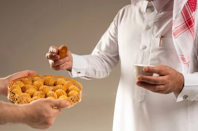 رجل سعودي يتناول المعمول مع القهوة العربية