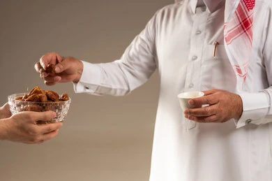 رجل سعودي يحمل فنجان قهوة عربية وتمر في استوديو