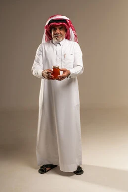 رجل سعودي مسن يحمل جرة عسل طبيعي