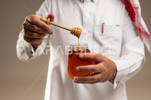 رجل سعودي يحمل برطمان عسل مع ملعقة خشبية