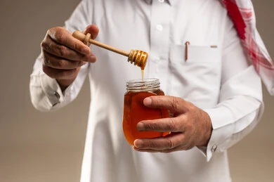 رجل سعودي يحمل برطمان عسل مع ملعقة خشبية