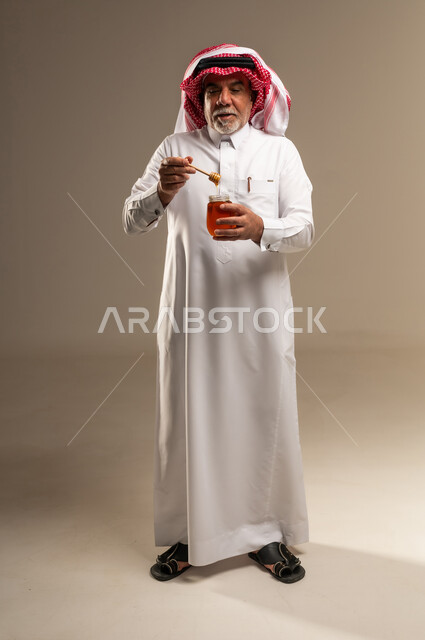 Elderly Saudi Man Holding Honey Jar in Studio