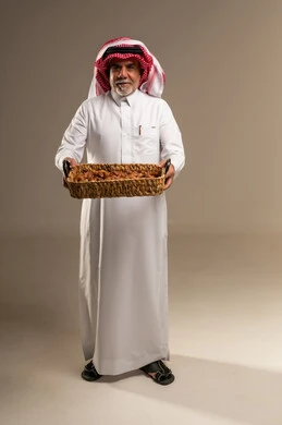 رجل سعودي يحمل سلة تمور في استوديو