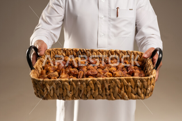 رجل سعودي يحمل سلة من التمور المجففة